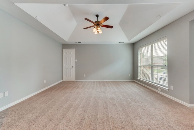 carpeted empty room with a raised ceiling and ceiling fan