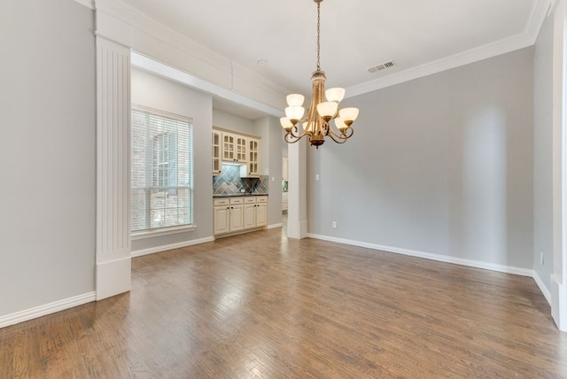 interior space with an inviting chandelier, ornamental molding, and hardwood / wood-style floors