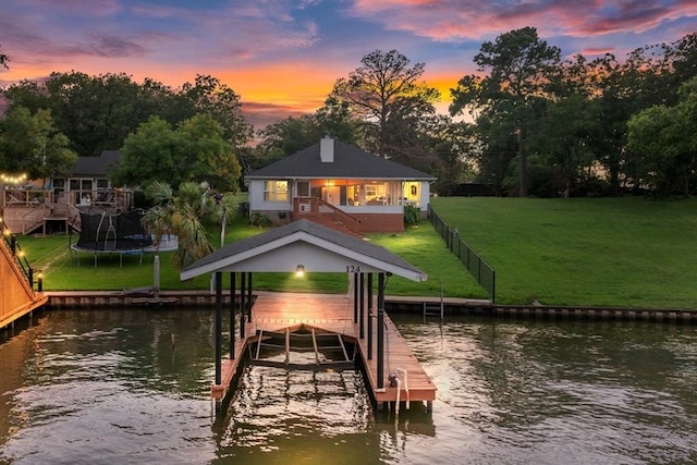 view of dock with a water view and a lawn