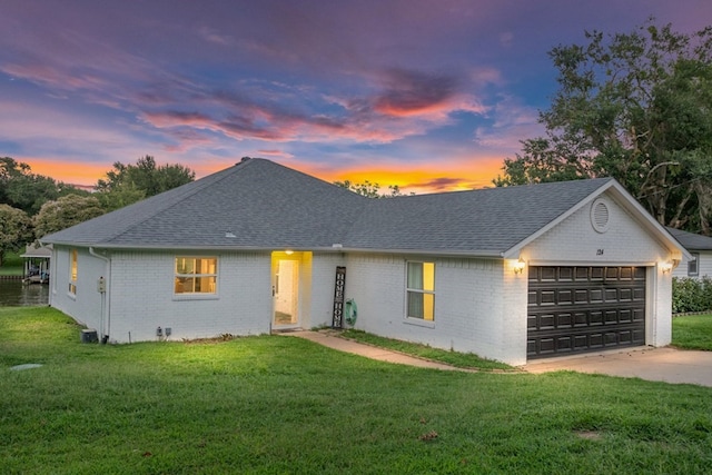 ranch-style home featuring a garage and a lawn