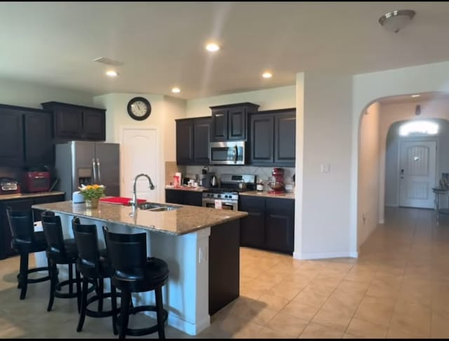 kitchen featuring sink, stainless steel appliances, a kitchen island with sink, a breakfast bar, and light tile patterned flooring