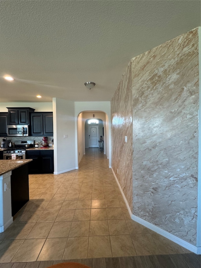 kitchen featuring a textured ceiling, stainless steel appliances, tasteful backsplash, and light tile patterned flooring