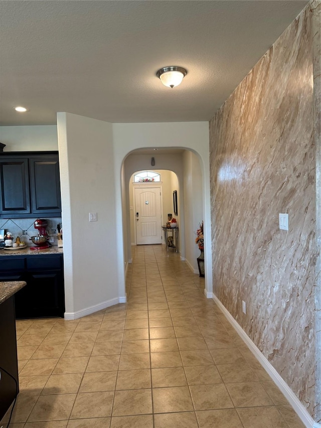 hallway with a textured ceiling and light tile patterned flooring