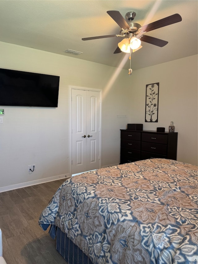 bedroom with ceiling fan, dark wood-type flooring, and a closet