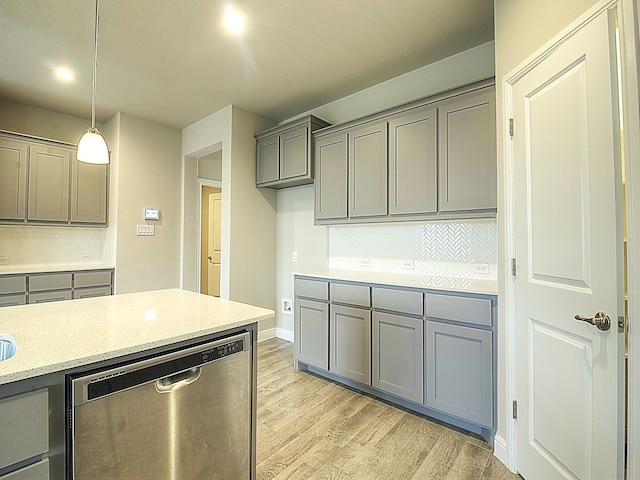 kitchen with light stone counters, hanging light fixtures, backsplash, light wood-type flooring, and dishwasher