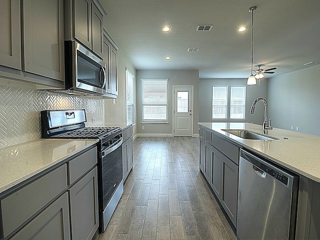 kitchen with backsplash, ceiling fan, hardwood / wood-style floors, appliances with stainless steel finishes, and sink