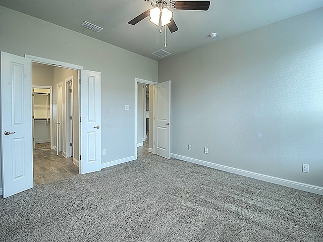 unfurnished bedroom featuring a spacious closet, ceiling fan, and carpet flooring