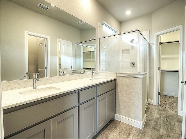 bathroom with an enclosed shower, hardwood / wood-style flooring, and dual bowl vanity