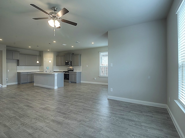 unfurnished living room with hardwood / wood-style floors, ceiling fan, and a wealth of natural light