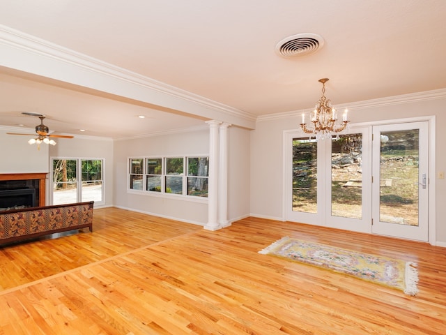 unfurnished living room with ceiling fan with notable chandelier, light hardwood / wood-style floors, crown molding, and decorative columns