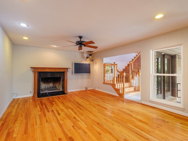 unfurnished living room featuring a tile fireplace, light wood-type flooring, and ceiling fan