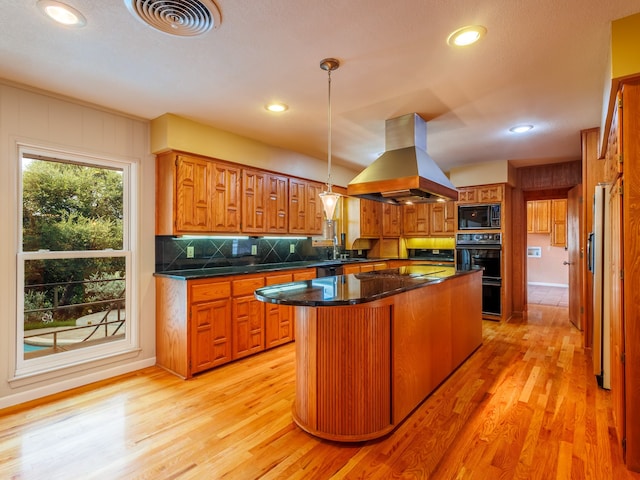 kitchen featuring a kitchen island, black microwave, light hardwood / wood-style floors, island exhaust hood, and decorative light fixtures