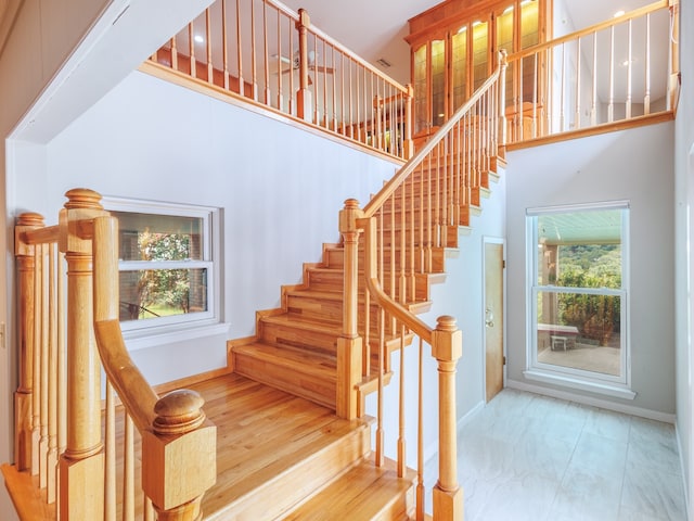 stairway with tile patterned flooring and a towering ceiling