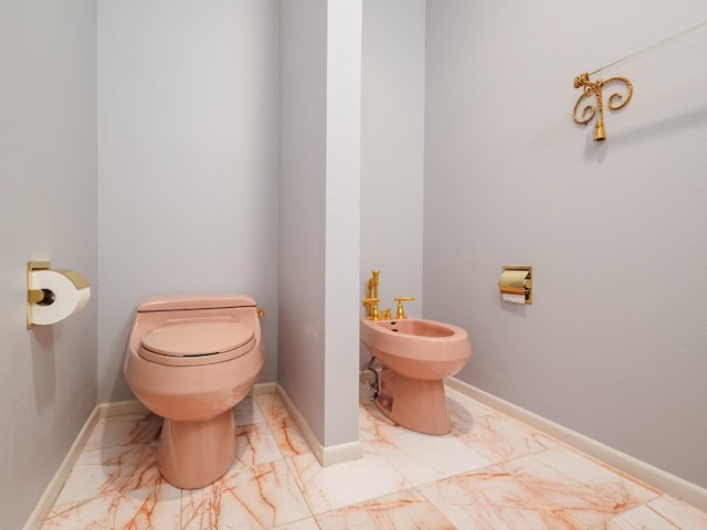 bathroom featuring tile patterned flooring, toilet, and a bidet