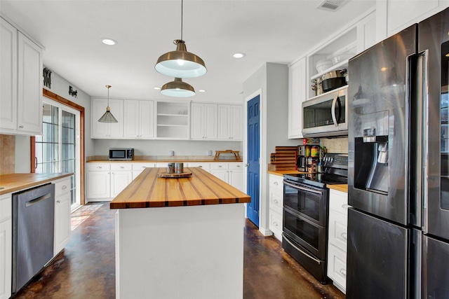 kitchen with butcher block counters, white cabinetry, decorative light fixtures, appliances with stainless steel finishes, and a kitchen island