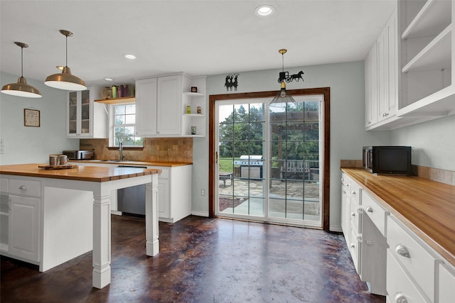 kitchen with wood counters, decorative light fixtures, dishwashing machine, and white cabinets