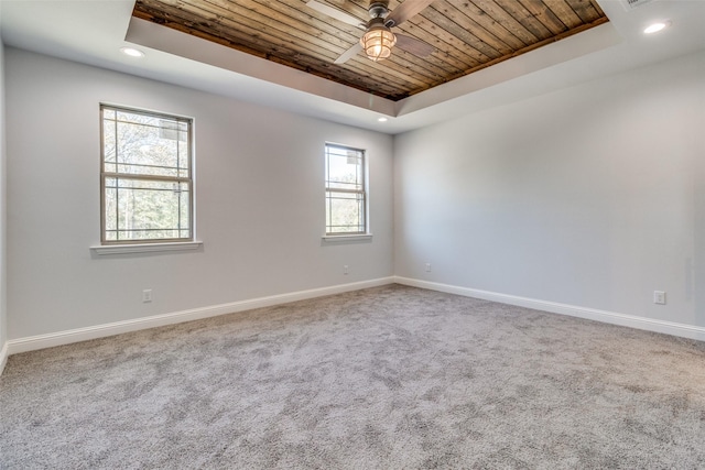 carpeted spare room featuring a healthy amount of sunlight, a raised ceiling, ceiling fan, and wooden ceiling