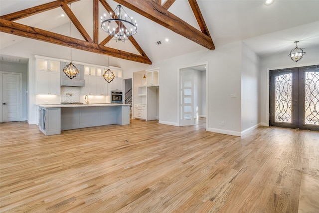 kitchen featuring stainless steel oven, french doors, a spacious island, tasteful backsplash, and decorative light fixtures