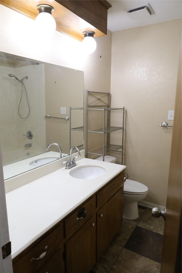 full bathroom featuring vanity, tile patterned flooring, tiled shower / bath combo, and toilet