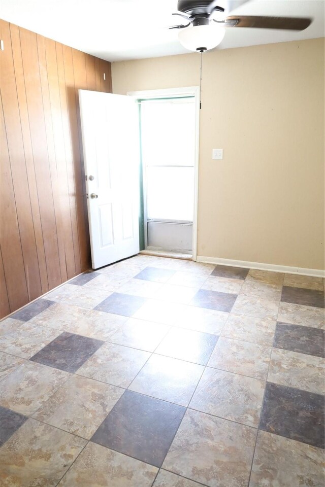 tiled spare room with wood walls and ceiling fan