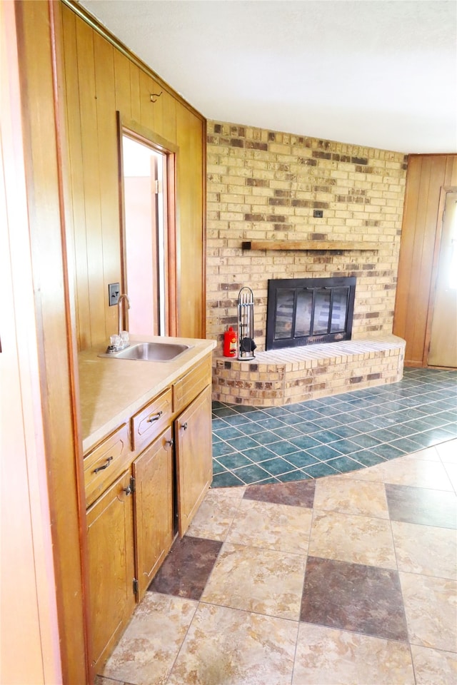 interior space featuring sink, a brick fireplace, tile patterned flooring, and wooden walls