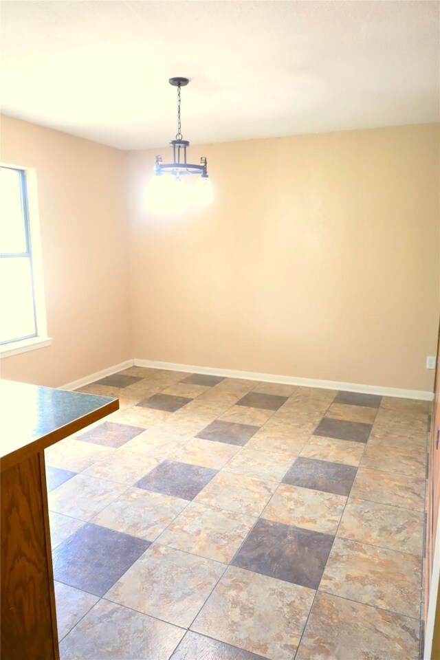 tiled empty room featuring a notable chandelier