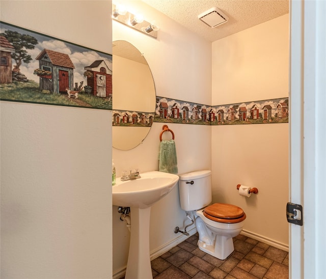 bathroom with sink, a textured ceiling, and toilet