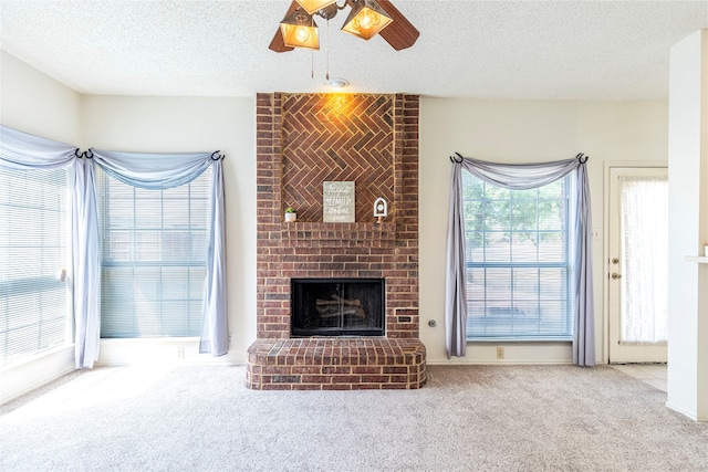 unfurnished living room with carpet flooring, a textured ceiling, ceiling fan, and a fireplace