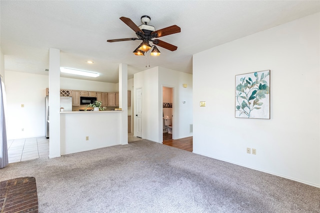 unfurnished living room featuring ceiling fan, light colored carpet, and a textured ceiling