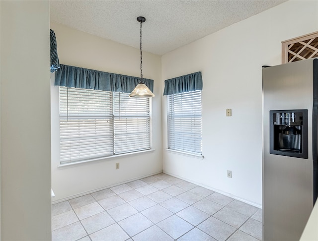 unfurnished dining area with light tile patterned flooring, a healthy amount of sunlight, and a textured ceiling