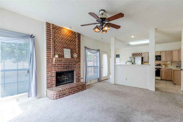 unfurnished living room featuring a textured ceiling, ceiling fan, light carpet, and a brick fireplace