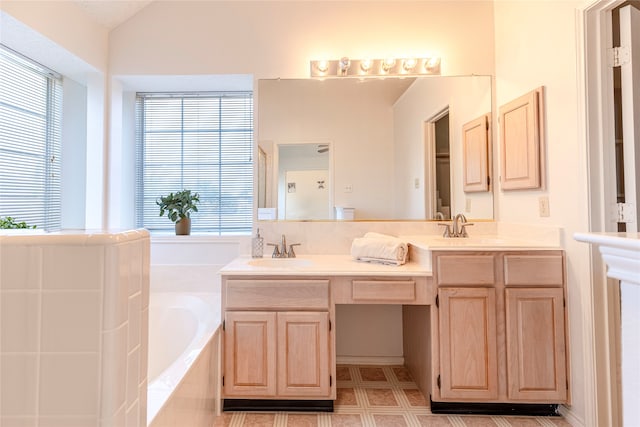 bathroom featuring vanity, plenty of natural light, lofted ceiling, and tiled tub