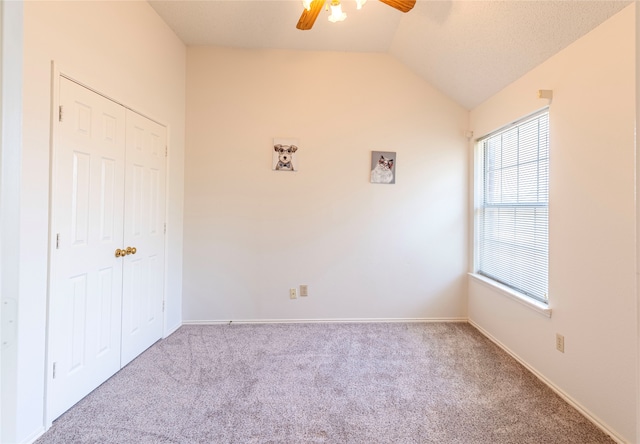 carpeted spare room featuring vaulted ceiling and ceiling fan