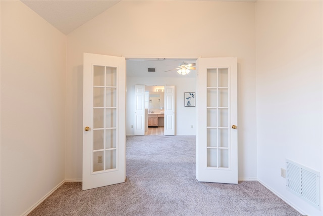 empty room with ceiling fan, french doors, light colored carpet, and lofted ceiling