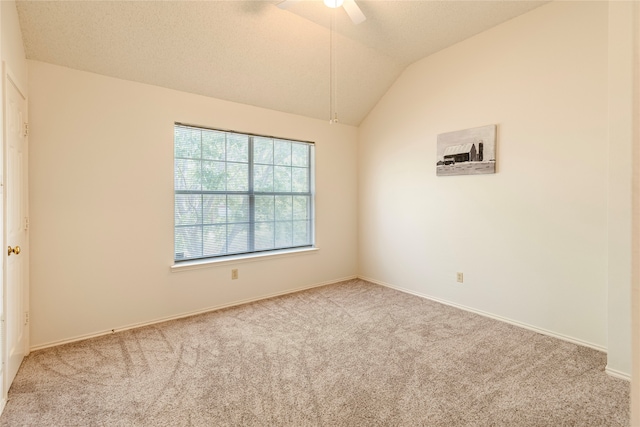 spare room with ceiling fan, light colored carpet, and vaulted ceiling