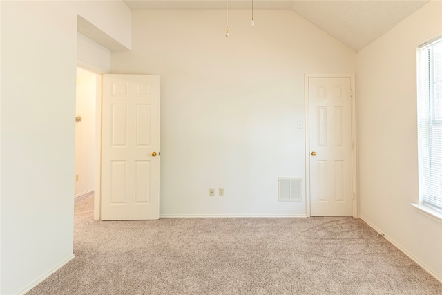 carpeted empty room with vaulted ceiling