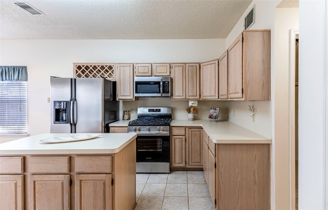 kitchen featuring light brown cabinetry, a textured ceiling, stainless steel appliances, and a kitchen island