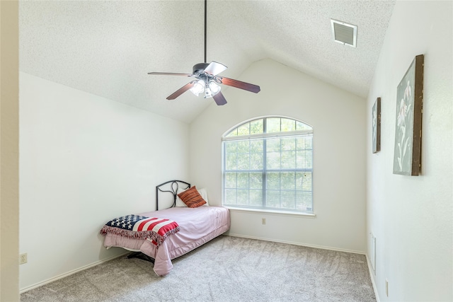 bedroom with a textured ceiling, ceiling fan, light colored carpet, and vaulted ceiling