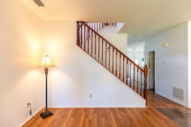 stairs featuring hardwood / wood-style flooring and a textured ceiling