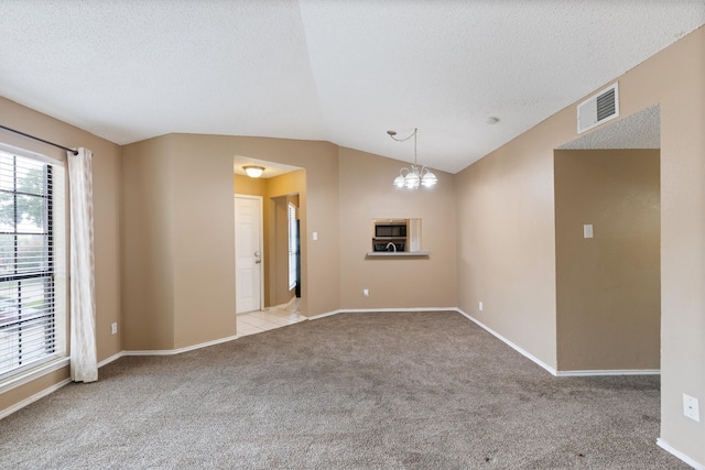 carpeted spare room with vaulted ceiling, a chandelier, and a textured ceiling