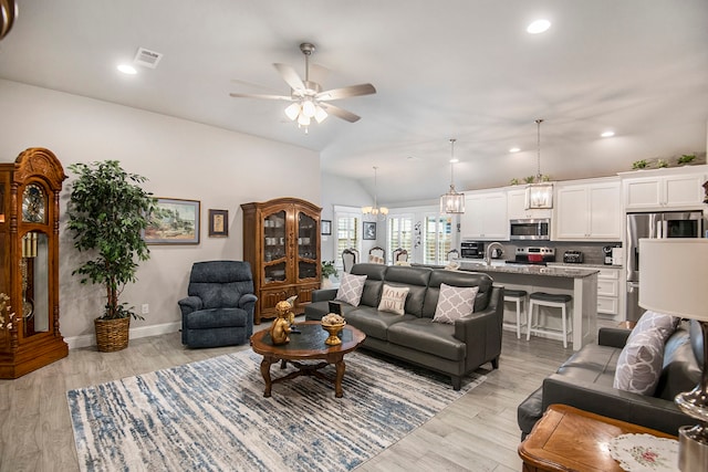 living room featuring lofted ceiling, light hardwood / wood-style flooring, sink, and ceiling fan