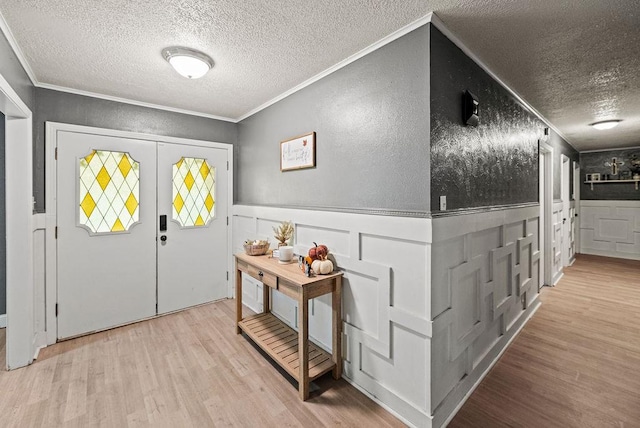 entrance foyer with light hardwood / wood-style flooring, a textured ceiling, and ornamental molding