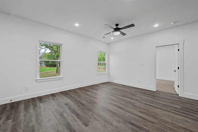 spare room with a healthy amount of sunlight, ceiling fan, and dark hardwood / wood-style flooring