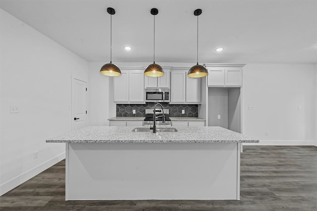 kitchen with sink, light stone countertops, hanging light fixtures, a center island with sink, and white cabinets