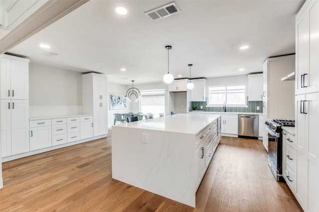 kitchen with pendant lighting, a center island, light hardwood / wood-style flooring, white cabinetry, and stainless steel appliances