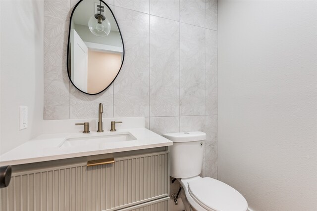 bathroom with vanity, tile walls, and toilet