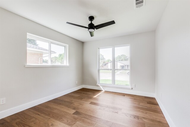 spare room with wood-type flooring, a wealth of natural light, and ceiling fan