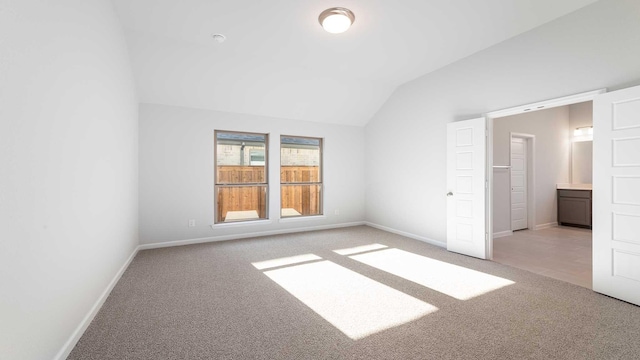 unfurnished room with light colored carpet and vaulted ceiling