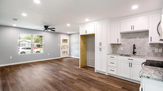 kitchen with tasteful backsplash, white cabinets, dark wood-type flooring, ceiling fan, and sink