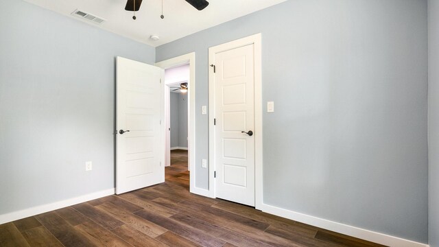 empty room featuring dark wood-type flooring and ceiling fan